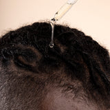 Hands applying Ginger Scalp Serum 50 ML in a professional studio setup with visible lighting gear.