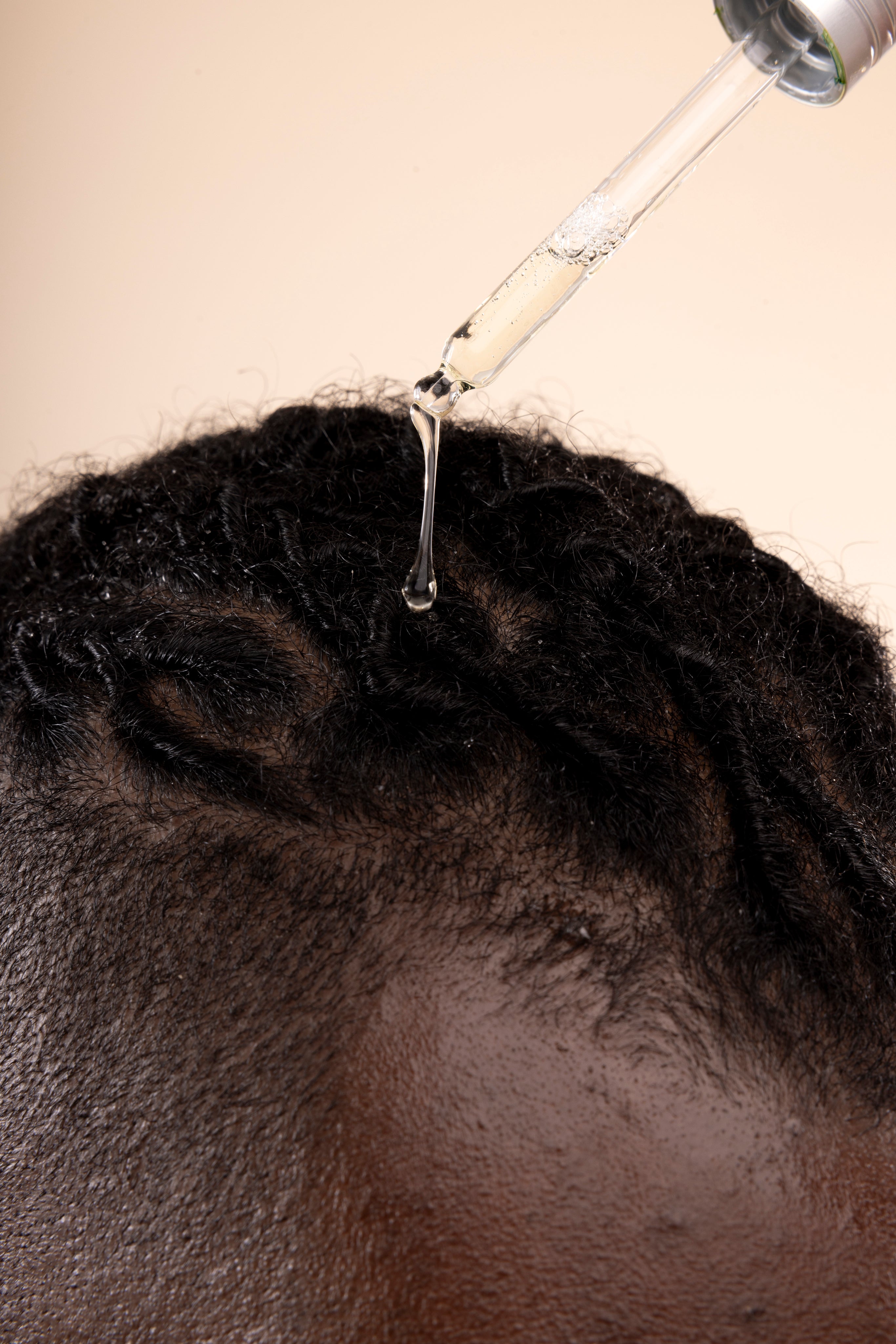 Hands applying Ginger Scalp Serum 50 ML in a professional studio setup with visible lighting gear.