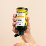 Hand dispensing The Body Shop Banana Truly Nourishing Shampoo 250 ML into palm.