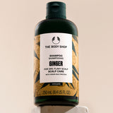 A bottle of The Body Shop Ginger Scalp Care Shampoo 250 ML on a clean backdrop with informative labeling.