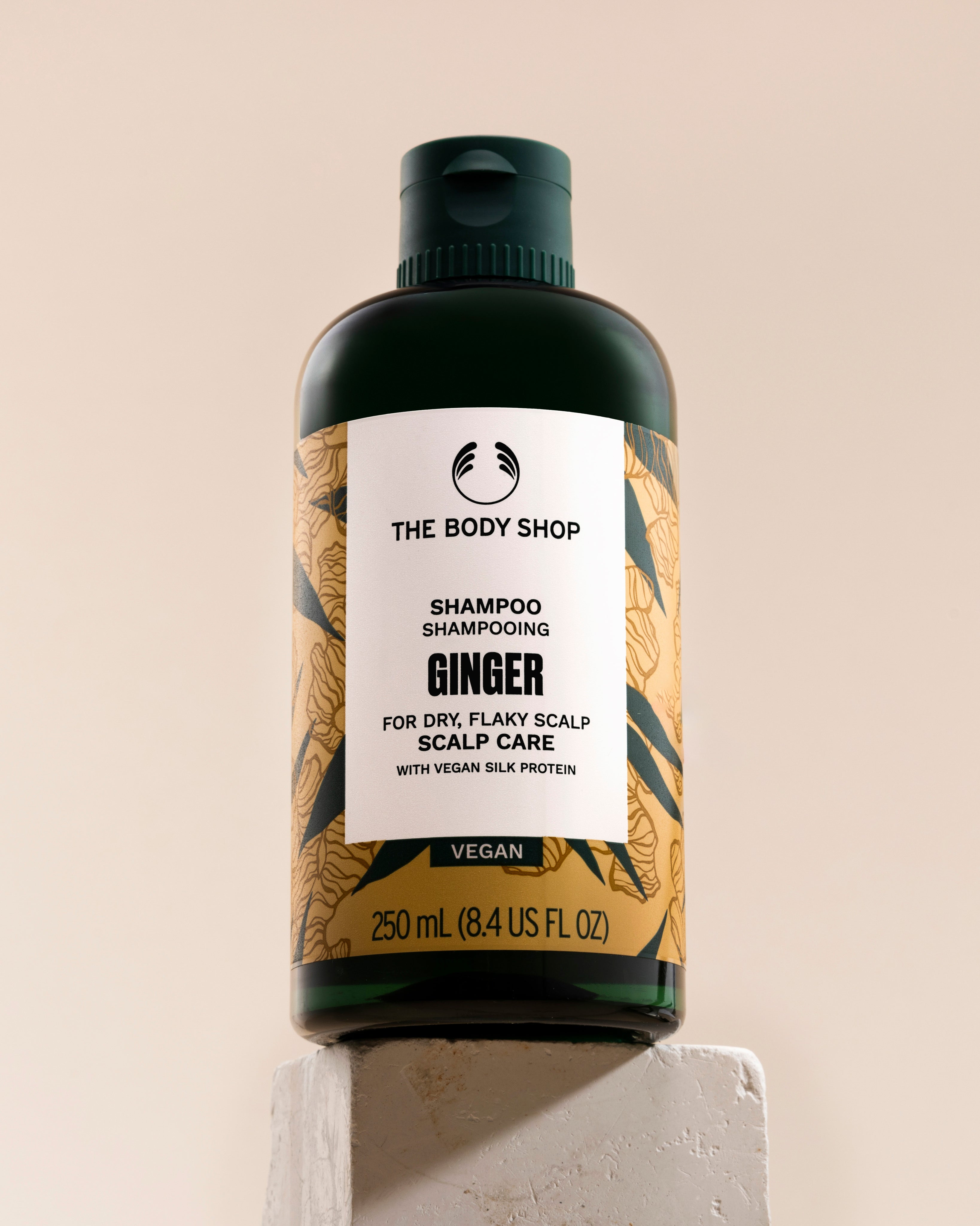 A bottle of The Body Shop Ginger Scalp Care Shampoo 250 ML on a clean backdrop with informative labeling.