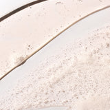 Close-up of ginger scalp care shampoo 250ml displaying bubbly texture against a clean background.