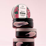 A stack of The Body Shop British Rose Body Butter 200ml against a soft pink backdrop.