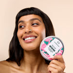 Woman smiling while holding The Body Shop British Rose Body Butter 200 ML against a soft, neutral background.