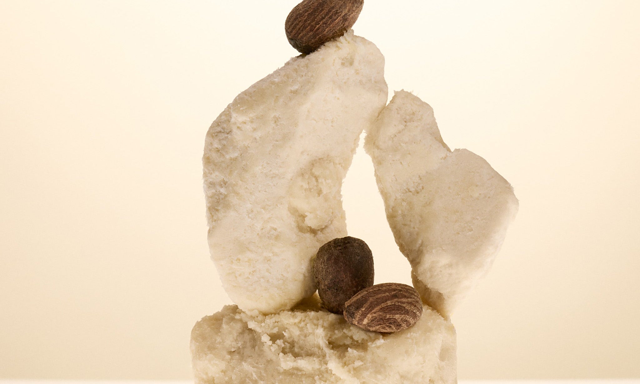 Decorative stone sculpture with a shea nut on top against a beige background