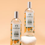 Visually appealing display of The Body Shop Satsuma Body Mist 100 ML against soft orange background
