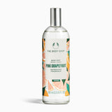 A bottle of The Body Shop Pink Grapefruit Body Mist 100 ML against a vibrant, fruity background.