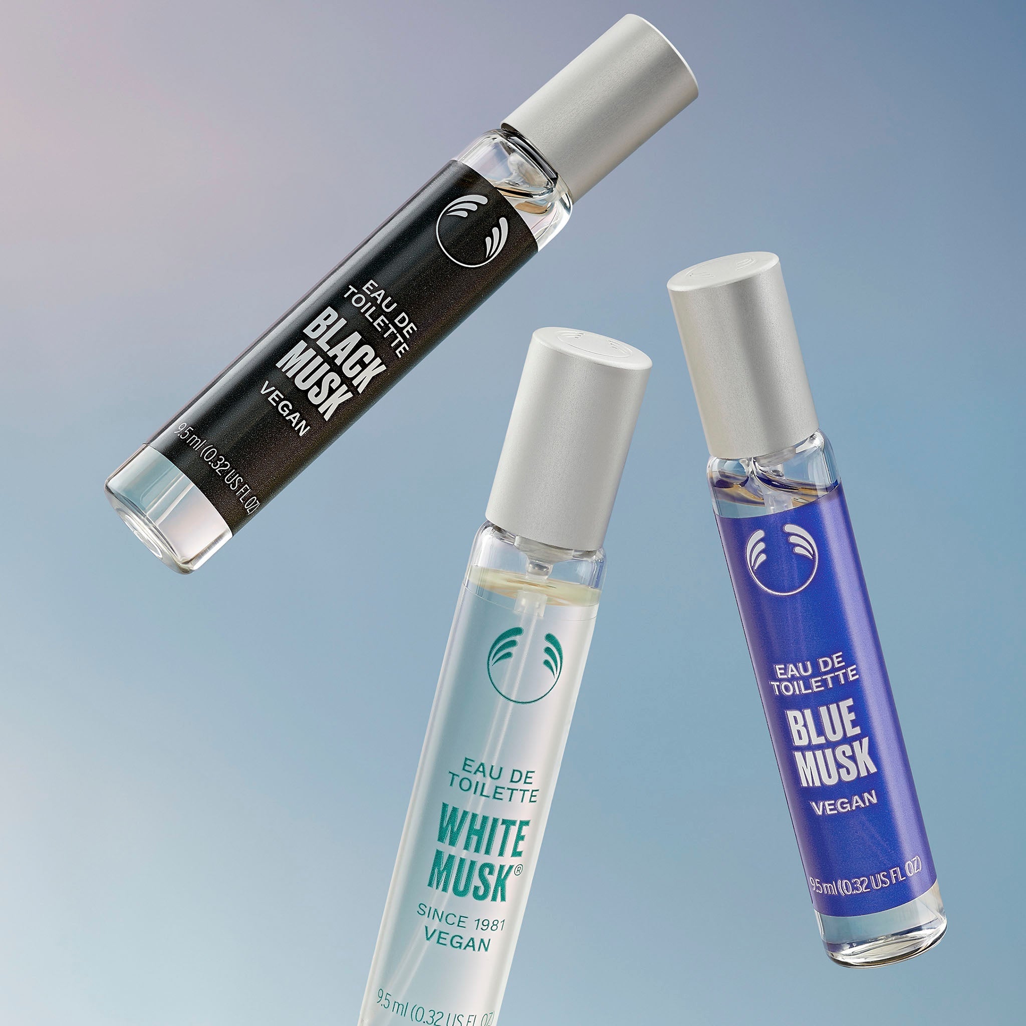 x3 9.5ML range of Eau De Toilettes, thrown up across a blue background - The Body Shop