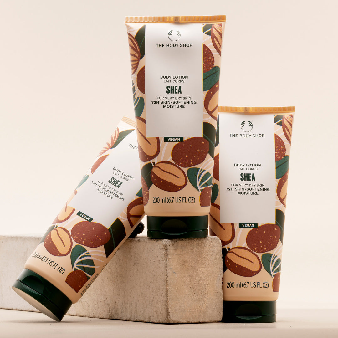 Two bottles of The Body Shop Shea body lotion on a beige background